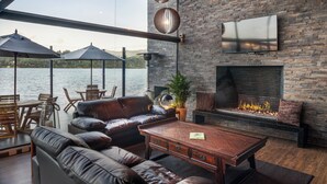 A modern outdoor living area with a stone wall, a fireplace, leather furniture, and a view of the water. - NAQUA  (Chocontá)