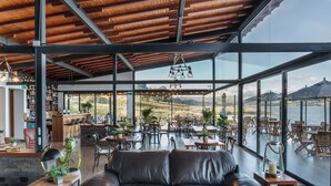 A spacious indoor area with a leather sofa, dining tables, and chairs, overlooking a scenic outdoor view. - NAQUA  (Chocontá)