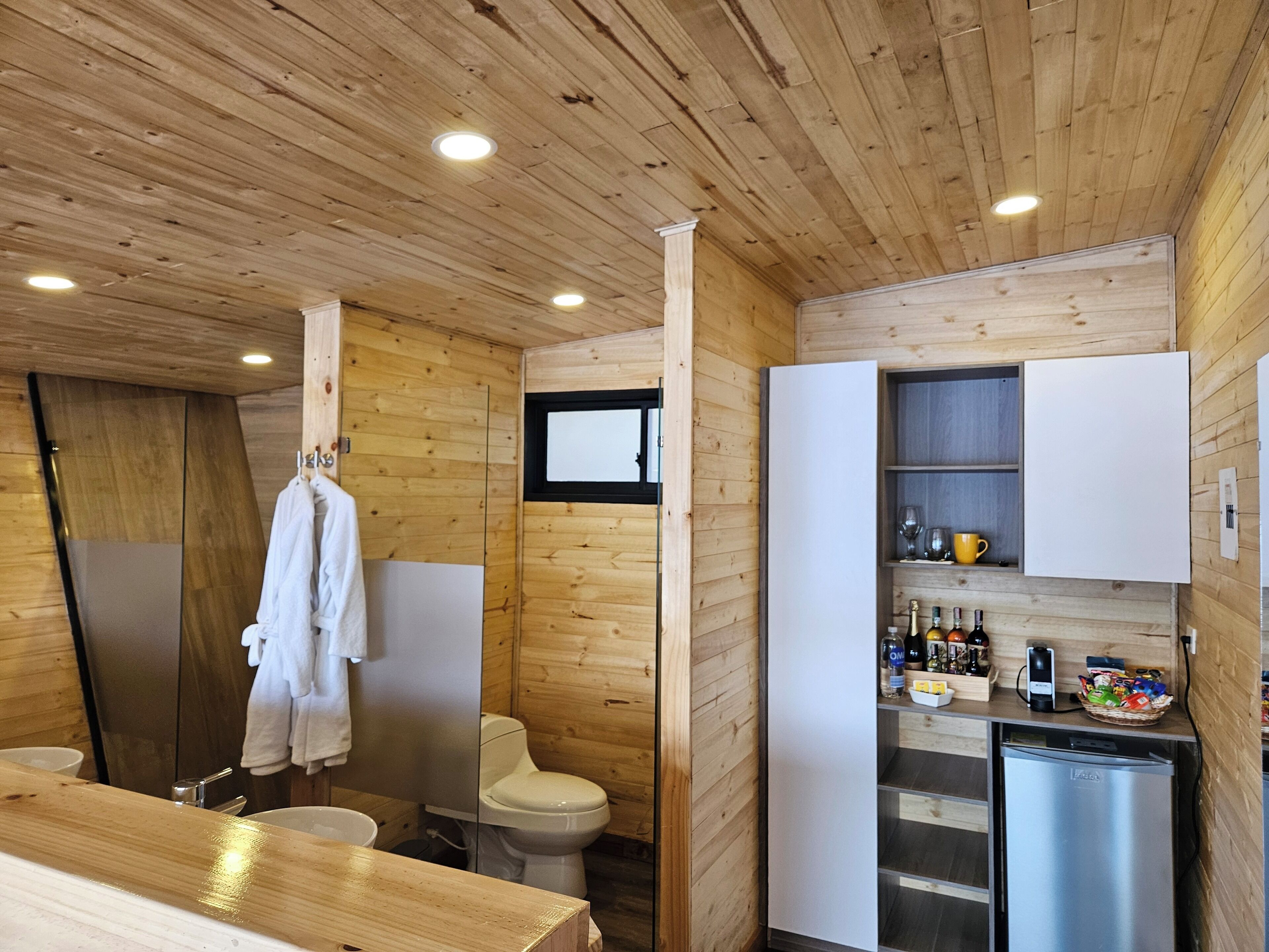 Une petite salle de bain avec un plafond en bois, un lavabo blanc et des toilettes.