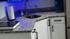 Een moderne keuken met witte kasten, een roestvrijstalen spoelbak, een magnetron en een koelkast.