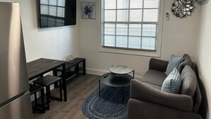 Een knus verblijf met een kitchenette, een eettafel, een bank en een ronde salontafel.