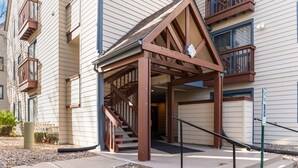 A building entrance with a covered staircase, a gated driveway, and a clear view of the building's exterior.