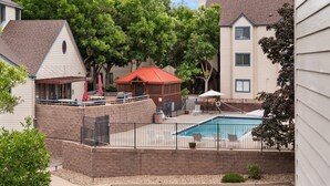 A residential area with a swimming pool, patio furniture, and a covered seating area.