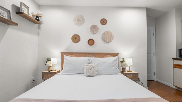 A neatly arranged bedroom with a large bed, bedside tables with lamps, and wall-mounted decorative plates.