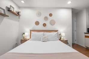 A neatly arranged bedroom with a large bed, bedside tables with lamps, and wall-mounted decorative plates.