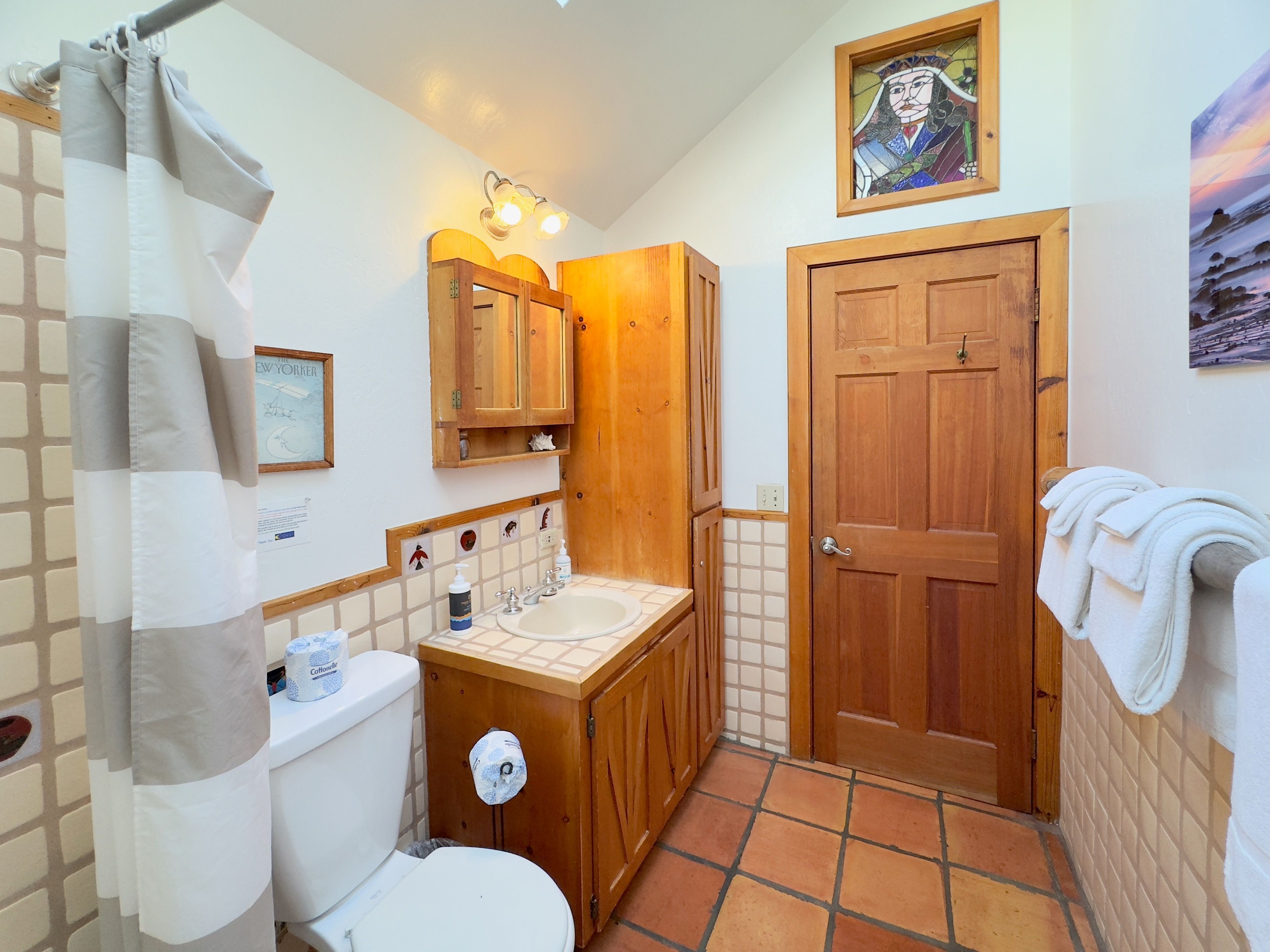 A bathroom with a toilet, sink, wooden cabinet, and a shower curtain.