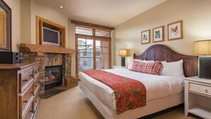 Un dormitorio con una cama grande, una chimenea, un televisor y una mesita de noche.