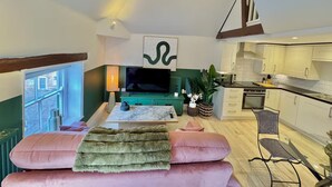 Un salon moderne avec un canapé, un téléviseur et une vue sur l’extérieur.