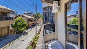 Un immeuble d’habitation doté d’un balcon, une rue pavée et des maisons voisines.