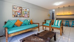 Un salon comprenant un canapé, deux fauteuils en bois, une table basse et des œuvres d’art accrochées au mur.