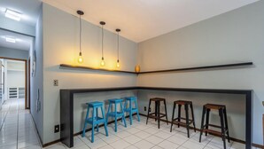 Une cuisine moderne dotée d’un îlot central, de tabourets de bar bleus et de luminaires suspendus.