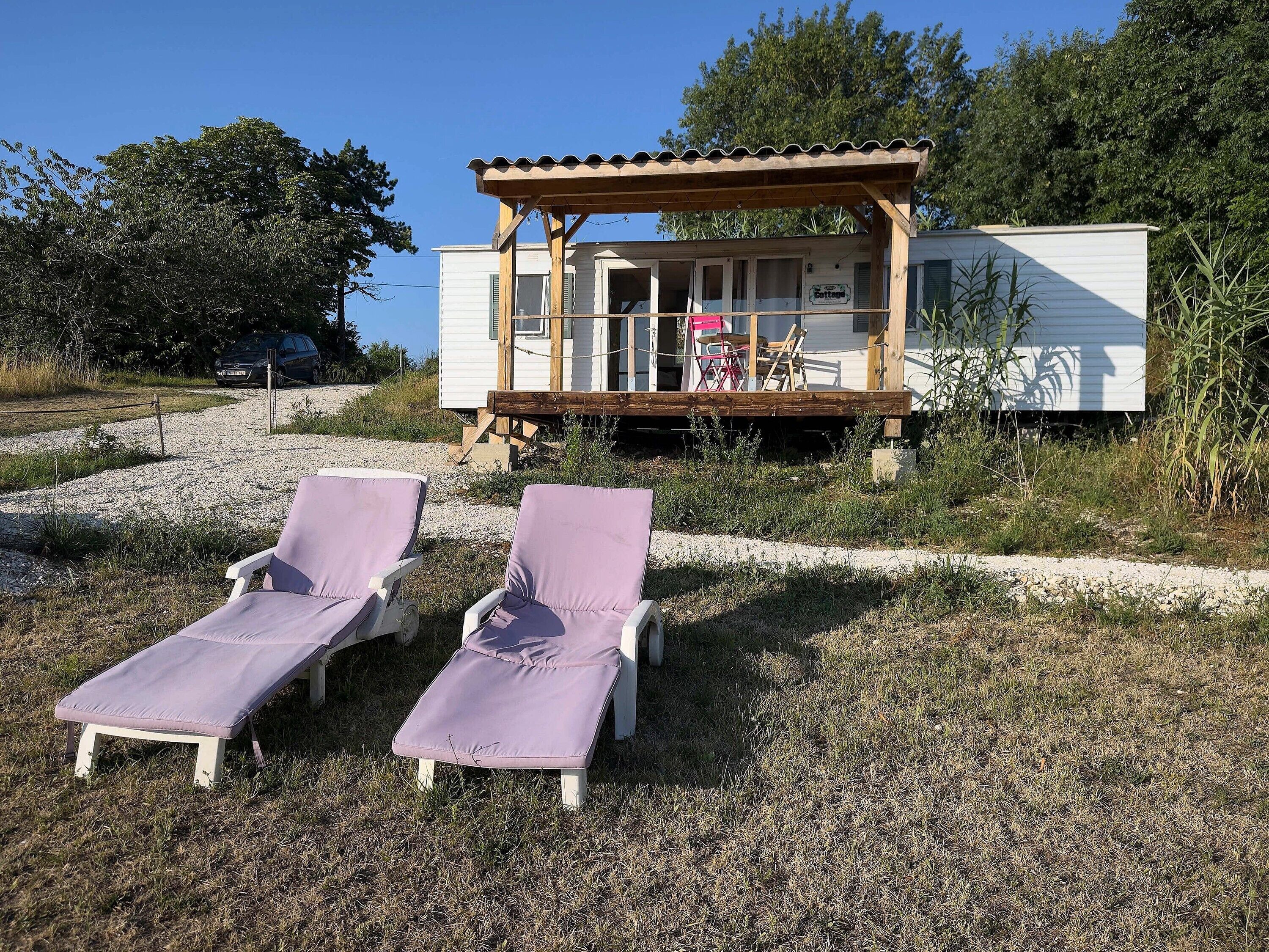 Una casa sulla spiaggia con un patio in legno e due poltrone da relax.