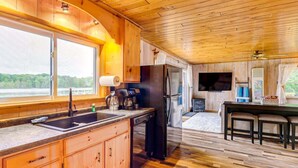 L’intérieur d’une cabane en bois comprend un coin cuisine équipé d’un évier, d’une cuisinière et d’un réfrigérateur, ainsi qu’un coin repas avec une table et des chaises.