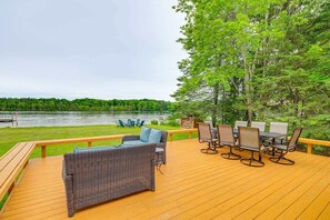 Une terrasse dotée de mobilier d’extérieur, d’une table et de chaises, offrant une vue sur un lac.