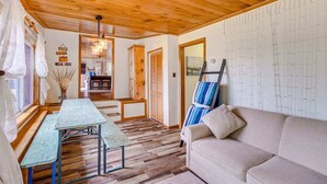 Une pièce chaleureuse avec un plafond en bois, une table à manger avec des bancs, un canapé et un mur décoré de motifs.