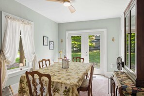 Comedor con una mesa dispuesta para cuatro, un ventilador de techo y vistas al exterior.