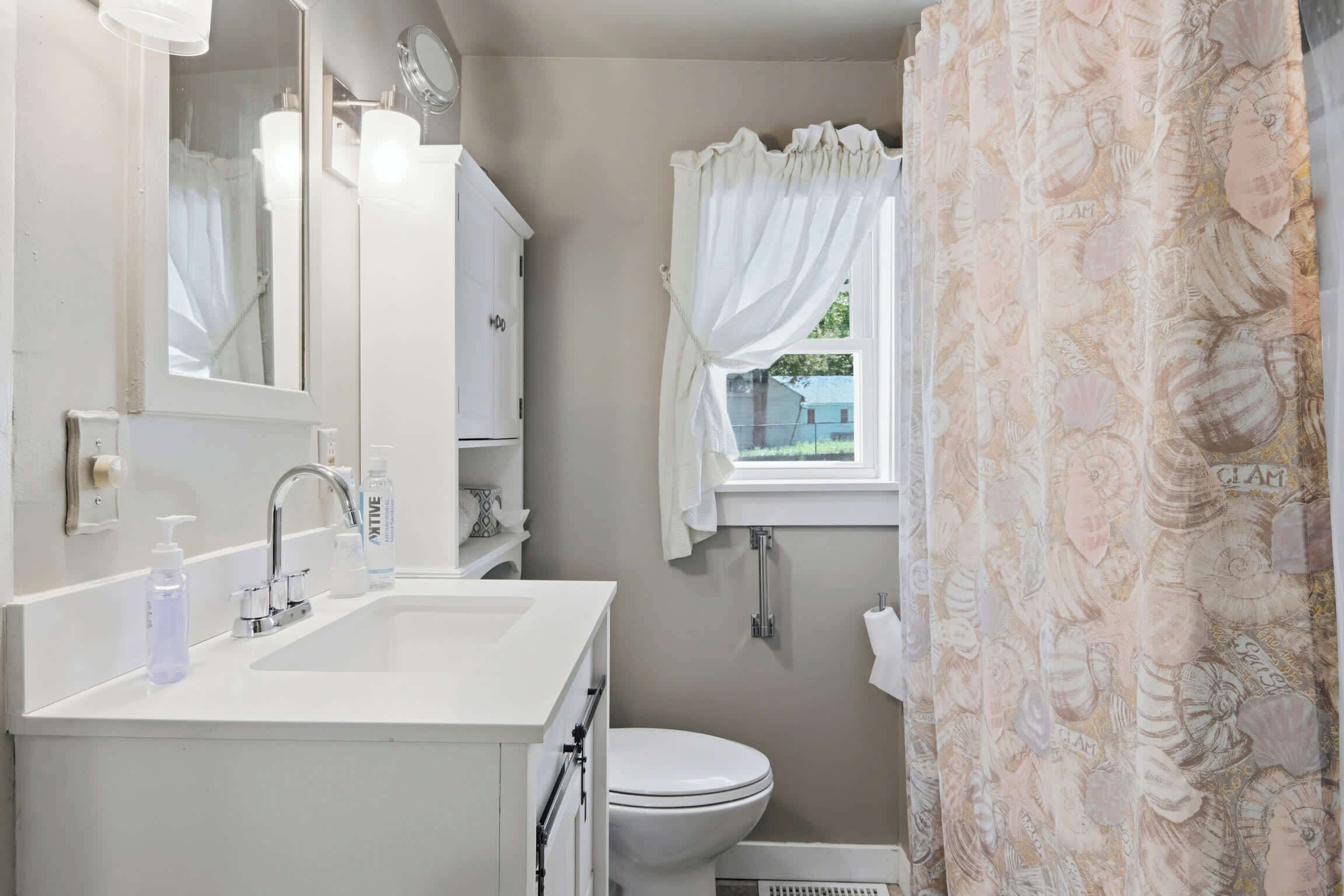 A bathroom with a white sink, mirror, and toilet.