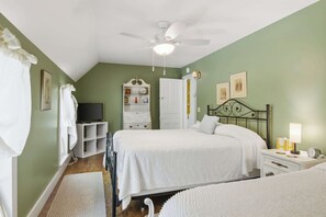 A bedroom with two beds, a ceiling fan, a television, and a white dresser.
