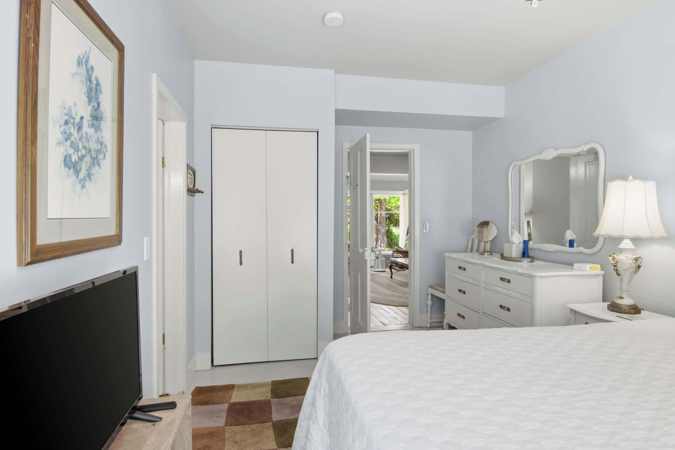 Une chambre à coucher comprenant un lit, une télévision, une armoire, une commode et un miroir.