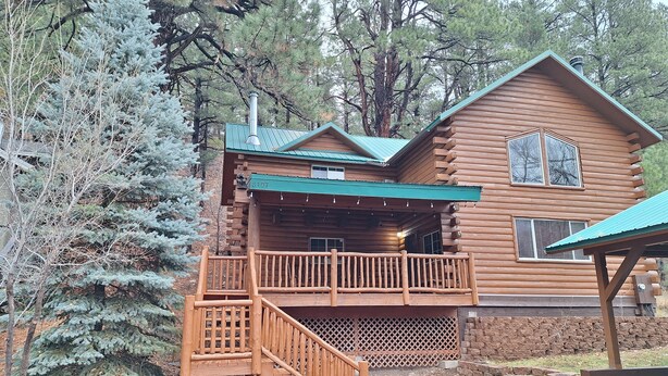 Une cabane en rondins avec une terrasse en bois et un porche abrité.