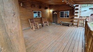 Une cabane en bois avec une véranda, des fauteuils à bascule et un banc.