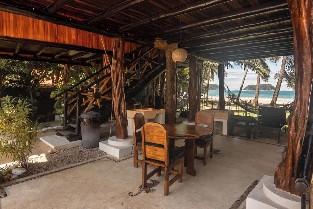A covered outdoor seating area with a view of the beach.