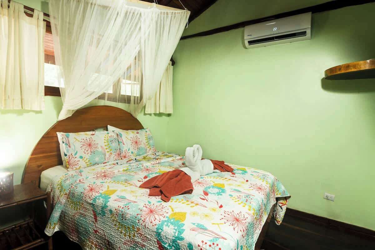 A bed with a floral bedspread, a white canopy, and a wooden headboard.