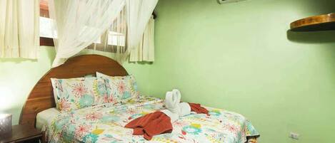 A bed with a floral bedspread, a white canopy, and a wooden headboard.