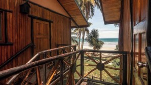 Ein Holzbalkon mit Blick auf Strand und Palmen.