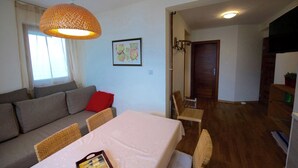 Ein gemütliches Wohnzimmer mit einer Couch, einem Esstisch und einer Pendelleuchte.