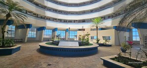 Un vaste atrium doté d’une fontaine centrale, de plusieurs niveaux et de plantes en pot.