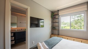 Una camera da letto con un letto, una TV, una finestra vista, un armadio e uno scaffale con piante.