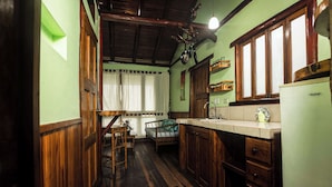 Cocina compacta con armarios de madera, un lavamanos y un comedor con una silla y una mesa.