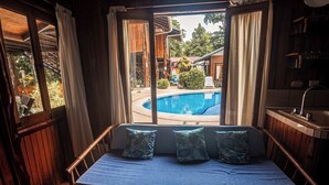Una habitación de madera con una cama, una ventana con cortinas y vista a una piscina.