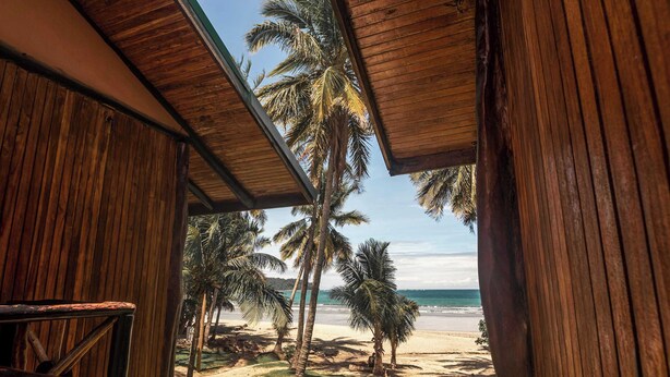 Una estructura de madera con vista a una playa y palmeras.