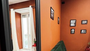 Ein Zimmer mit einem großen Spiegel, einem grünen Sofa und Blick auf einen Balkon mit Vorhängen.