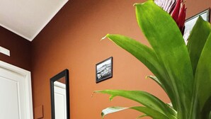 Ein Zimmer mit einem grünen Sofa, einem roten Blumentopf, einem Marmorboden und einem gerahmten Bild an der Wand.