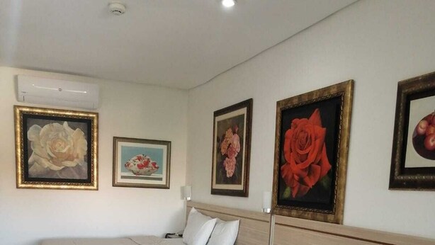 A hotel room with four beds, a wooden headboard, and three framed floral paintings on the wall. - aparthotel Maison Suisse (Asunción)