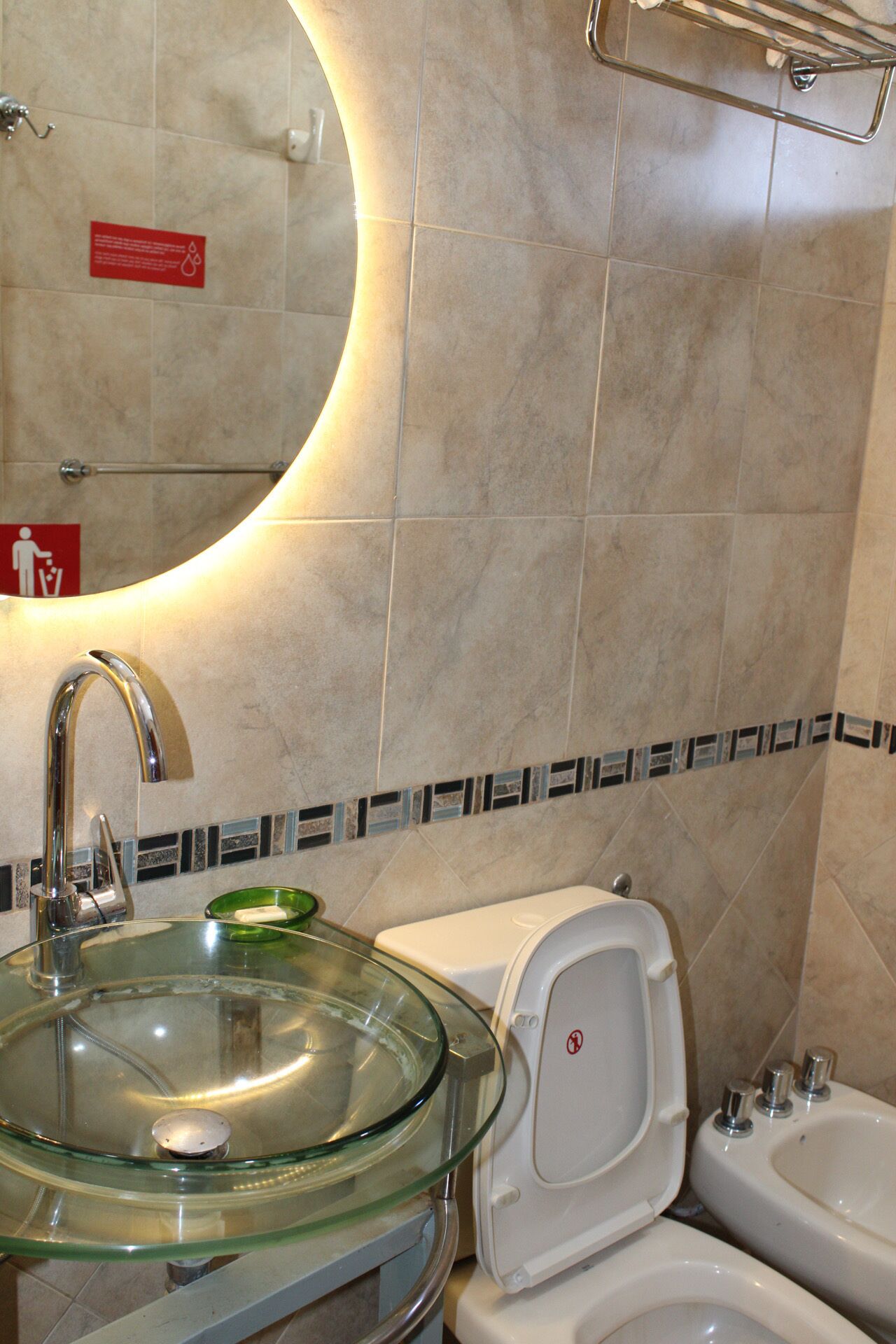 Un baño con lavabo de vidrio, inodoro y bidé.