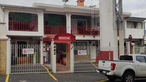 A building with a red and white facade, a gated entrance, and a sign reading "MALUTIN 482". - aparthotel Maison Suisse (Asunción)