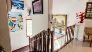 A staircase with wooden balusters, a tiled floor, and a ceiling with wooden panels. - aparthotel Maison Suisse (Asunción)