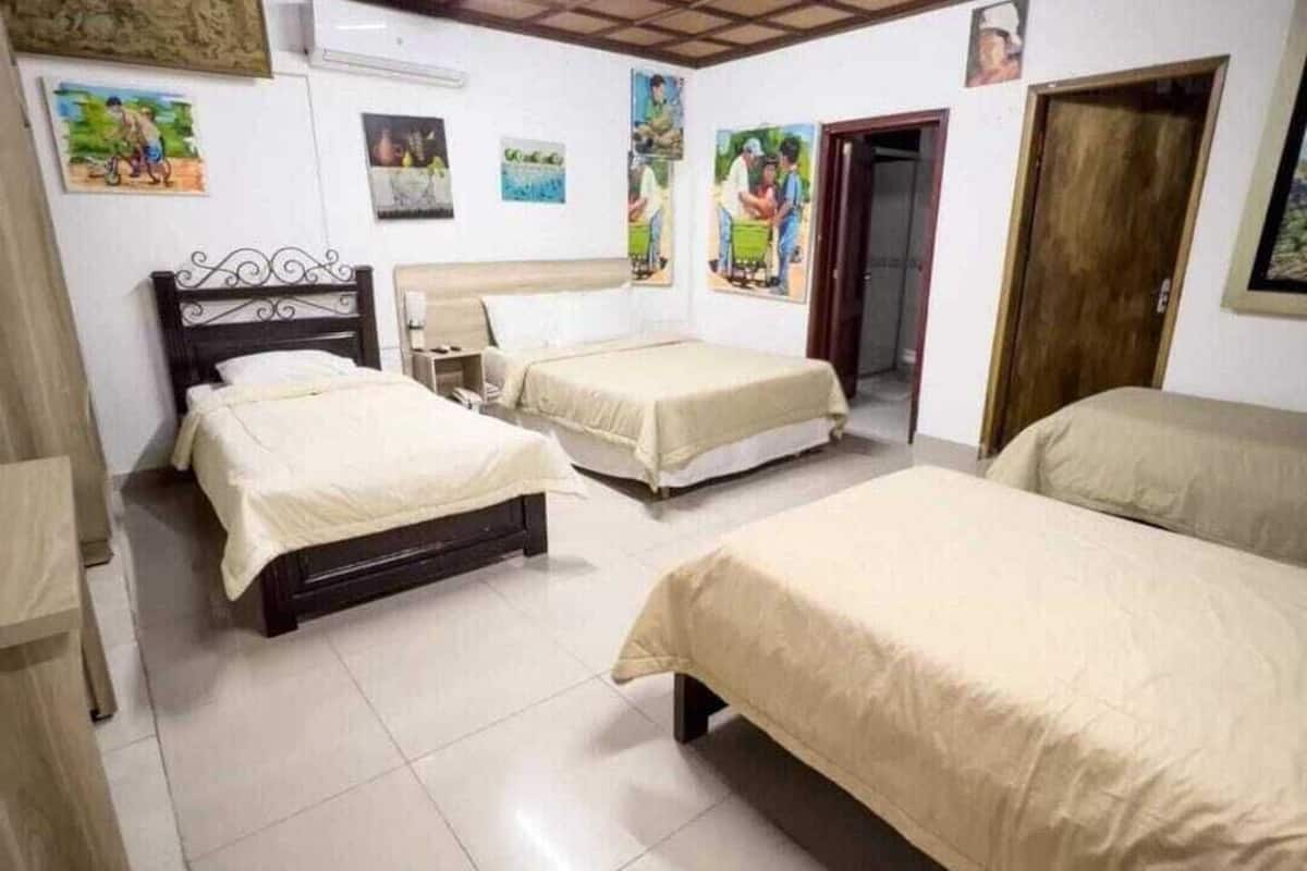 Habitación con tres camas, techo de madera y suelo de baldosas.