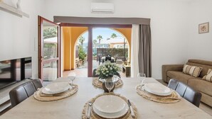 Un coin repas avec une table dressée pour quatre personnes, un canapé et un téléviseur.