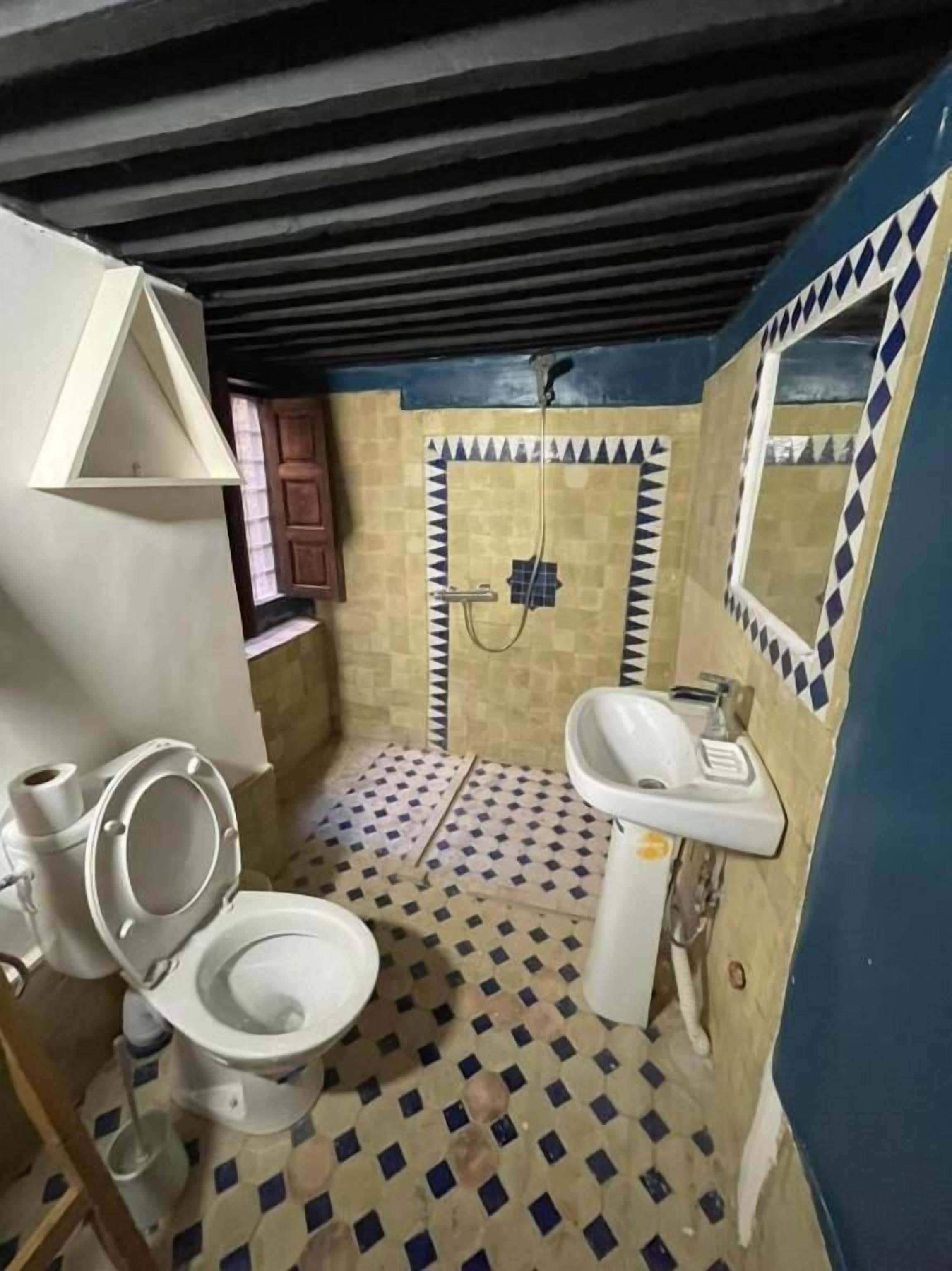 A small bathroom with a toilet, sink, and shower.