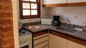 A kitchen with a gas stove, a toaster, a coffee maker, and a sink. - Vacances Centro (Pinamar)