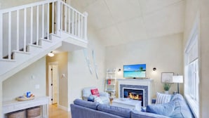 Ein geräumiges Wohnzimmer mit Kamin, einer großen Couch, einem Fernseher und einer Treppe.