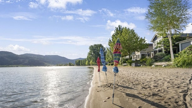 Ein Strand mit Sonnenschirmen und einem See.