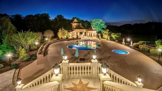 Une entrée imposante avec un motif de sol en forme d’étoile, une piscine et un bâtiment doté d’une tour.
