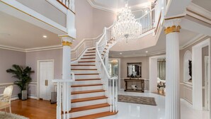 Un magnifique escalier, doté de rampes blanches et de marches en bois, menant à l’étage supérieur.