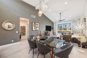 A modern dining area with a glass table, grey chairs, and pendant lighting. - Stunning, Fully Remodeled 2-Bed/2-Bath Residence in Serene Palm Desert (Palm Desert)